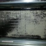 A dirty oven door with black paint on it.
